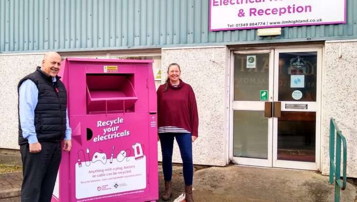 Image of ILM Highland's Martin Macleod (left) and Claire Weaver (right), standing next to a large pink donation bank, encouraging people to recycle their electricals
